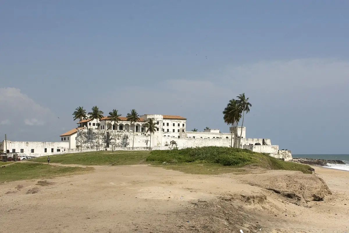 Elmina Castle seen across the grass beside the coast