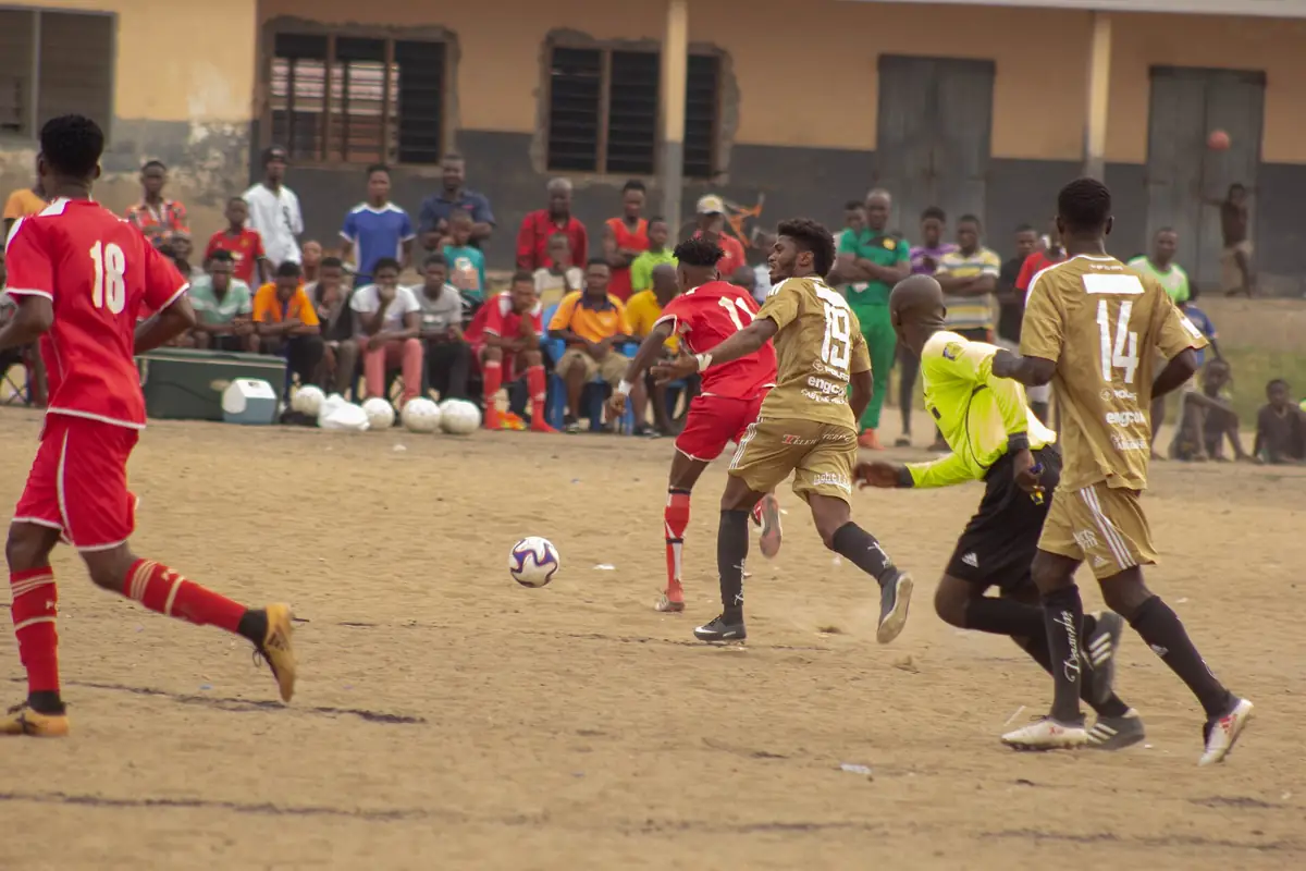 Players competing for the ball in a community football match in Ghana